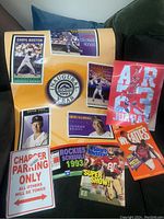 Wide shot of all items laid out on a surface including Rockies poster, lenticular Jordan art, Wheaties poster, magazine, and Charger sign