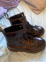 Side view of the two black 8-hole Doc Martens Chelsea boots showing leather upper, laces, and yellow stitching.