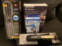 Photo shows full boxed Infiniti Pro Spin Air Brush alongside boxed Brookstone Daylight Therapy Lamp, UV Light Wand, and Kipozi straightener on bubble wrap.