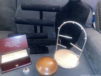 Image showing all items together including wooden jewelry box, porcelain trinket box, wooden music box, metal necklace display, and velvet displays on a gray couch.