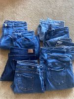 Image showing 10 pairs of ladies denim jeans in various shades of blue, folded and stacked in two rows.