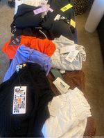 Black knit sweater and various colored tops with tags visible