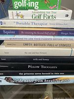 Stack of nine paperback books featuring titles related to golf, poetry, self-help, and personal stories.