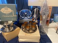 Photo of entire lot showing Viking stainless steel serving dish with ladle, FB Rogers silver plated pastry trowel in box, Astral lead crystal dish, silver plated bud vase, and silver plated small cups with tray