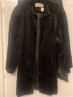 Front view of vintage black women's winter coat, showing plush texture and missing buttons.