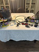 Overview of the lot items laid out on a white cloth-covered wooden table including air mattress bag, air pumps, locks, plugs, helmet, and motorbike pull start.