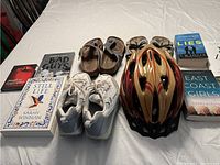 Overview of youth bike helmet, women's sandals, white athletic shoes, and six books including 'Still Life' and 'The Bad Guys'.