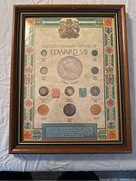 Front view of framed display showing Canadian coins from Edward VII era mounted on decorative matte with coat of arms and explanatory text