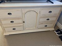 Front view of wooden dresser showing six drawers and central cabinet door with decorative chevron pattern.