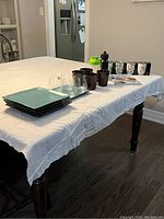 Table display of assorted housewares including plates, cups, tumblers, shakers, and decorative bucket containers.