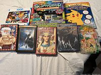 Group photo showing puzzle box, slime kit, drawing book, four DVDs, and pachinko toy together on a white cloth background.