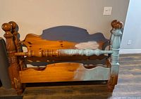 Full view of the assembled queen pine cannonball bed frame showing worn finish and primer areas.