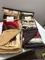 Both brand new throws folded and hung for display, showing full patterns and sherpa backing edges
