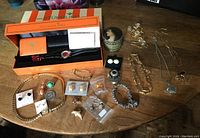 Overview of entire lot including watch in box and all jewelry pieces spread on table