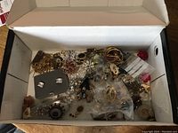 Top view of open box containing assorted costume jewelry pieces
