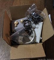 Box containing multiple pieces of costume jewelry including earrings, bracelet and loose rings/tassels
