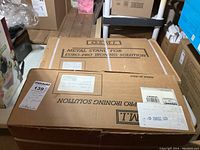 Closed cardboard boxes labeled 'Metal Stand for Euro-Pro Ironing Solution' and 'Euro Pro Ironing Solution', stacked and ready for transport.