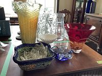 Photo of various glass and pottery items including vases, decorative pieces, and a pottery bowl on a dining table.
