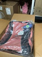 Five Heys chair covers in original packaging inside cardboard box. Coral colored, blue and black covers visible, made from recycled plastic bottles.