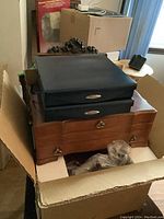 Multiple jewelry storage pieces grouped in one box, including a large wooden box and two smaller black cases
