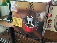 Front and side views of Keurig Compact coffee maker box showing product features and brand.