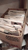 Box containing approximately 45 vintage Vogue sewing patterns with visible folded paper pattern envelopes.