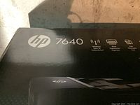 Close-up of HP Envy 7640 logo and wireless print/fax/copy/scan features on box.