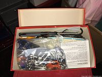 Box containing multiple scissors in plastic bags including orange handled and precision scissors