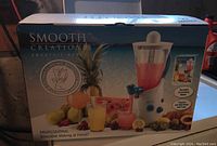 Front view of the box showing the Smooth Creations Smoothie Maker with images of fruit and a smoothie glass.