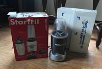 Starfrit blender box and Magic Bullet NutriBullet blender unit next to box on hardwood floor