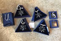 Top-down shot of six Swarovski snowflake ornaments in original boxes alongside branded bag