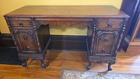 Full view of antique wooden desk showing front side with drawers and carved details.