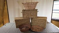 Photo showing six assorted wicker baskets arranged on a table including four rectangular and two round shapes.