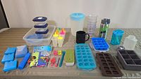 Wide view of entire lot showing storage containers, ice molds, mugs, water bottle, popsicle molds, and various kitchen accessories on a wooden table.