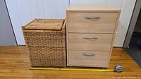 Photo showing the wicker laundry basket and wooden side table together with tape measure for scale