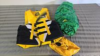 Yellow Fluid brand medium inflatable life jacket with black and white fasteners, uninflated and flat, accompanied by green crocodile inflatable float.
