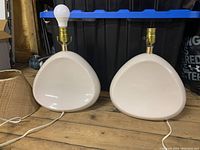 Pair of white mid-century modern teardrop-shaped ceramic lamp bases with brass lamp sockets. Lamps are unplugged and without shades in this photo.