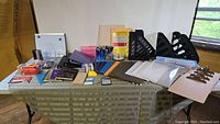 Overview of office supplies on table including clipboards, colored folders, pens, notebooks, document holders, and filing racks