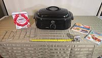 Full setup of Rival roaster oven, two meat racks, two cookbooks, and measuring tape showing size.