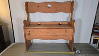 Front view of the small wooden bench showing heart-shaped cutout on backrest and seat/storage lid.