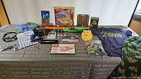 Full overview of all items laid out on table including shirts, puzzles, games, toys, and collectibles.