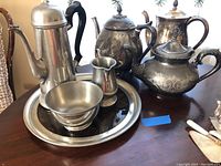 Overview photo of the full lot showing all coffee and tea pots, creamer, bowl, and tray arranged on a table.