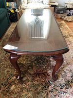 Front view of coffee table showing glass top and carved legs.
