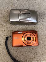 Olympus Stylus Epic Zoom 80 film camera and Nikon Coolpix digital camera side by side on carpet