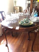 Wooden dining table with various glassware on top, showing table shape, size and wood tone.