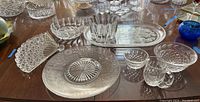 Glass serving plates, platters, Waterford crystal cream and sugar set, candy dish, and other glassware showing overall condition and details.