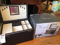 Jewelry trunk open with several compartments visible, next to its original box
