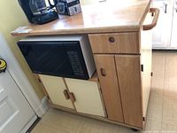 Front view of the woodblock kitchen cart showing top surface, microwave compartment, drawer, and cabinet doors.