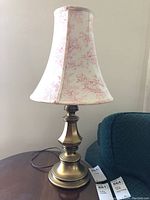 Full view of the table lamp showing brass base and red toile fabric shade.
