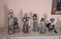 Five Lladro porcelain figurines displayed on a shelf, showing a woman at a fountain, a woman with a goose, a girl holding a bird, a child with flowers, and a girl in a dress with a hat.